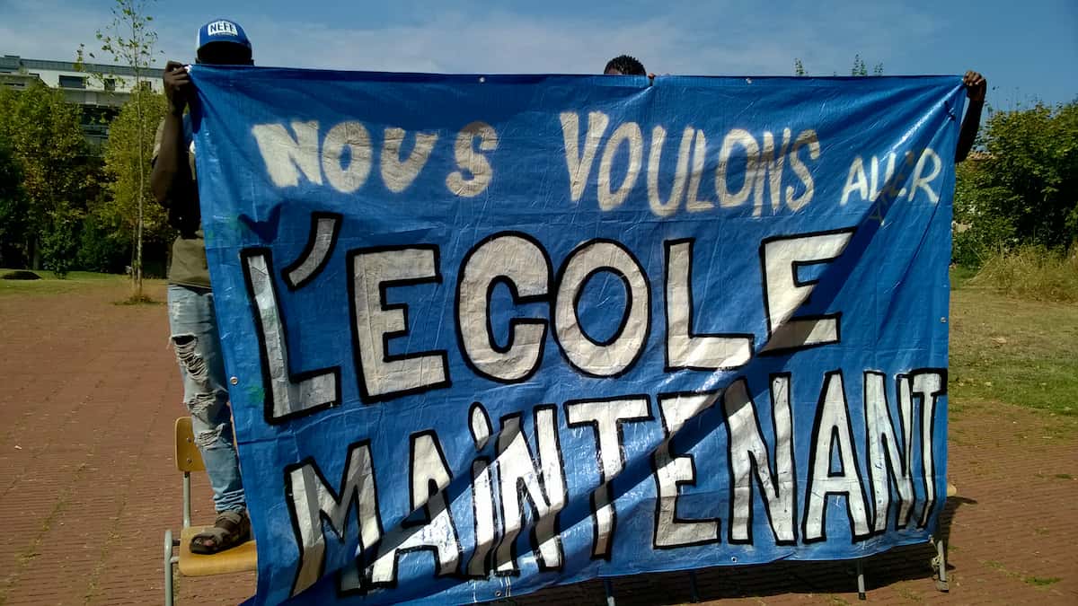 Mineurs Isolés étrangers tenant une banderole sur lequel il est écrit qu'ils veulent être scolarisés.